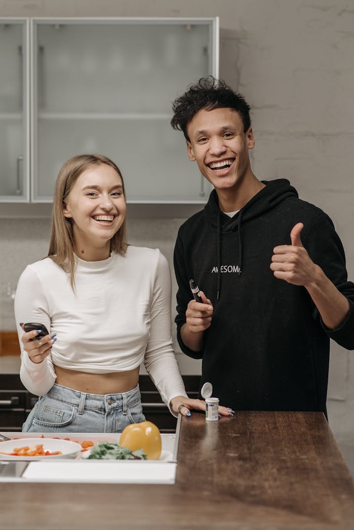 Smiling couple in kitchen holding glucometer and insulin pen, showing positivity in diabetes management.